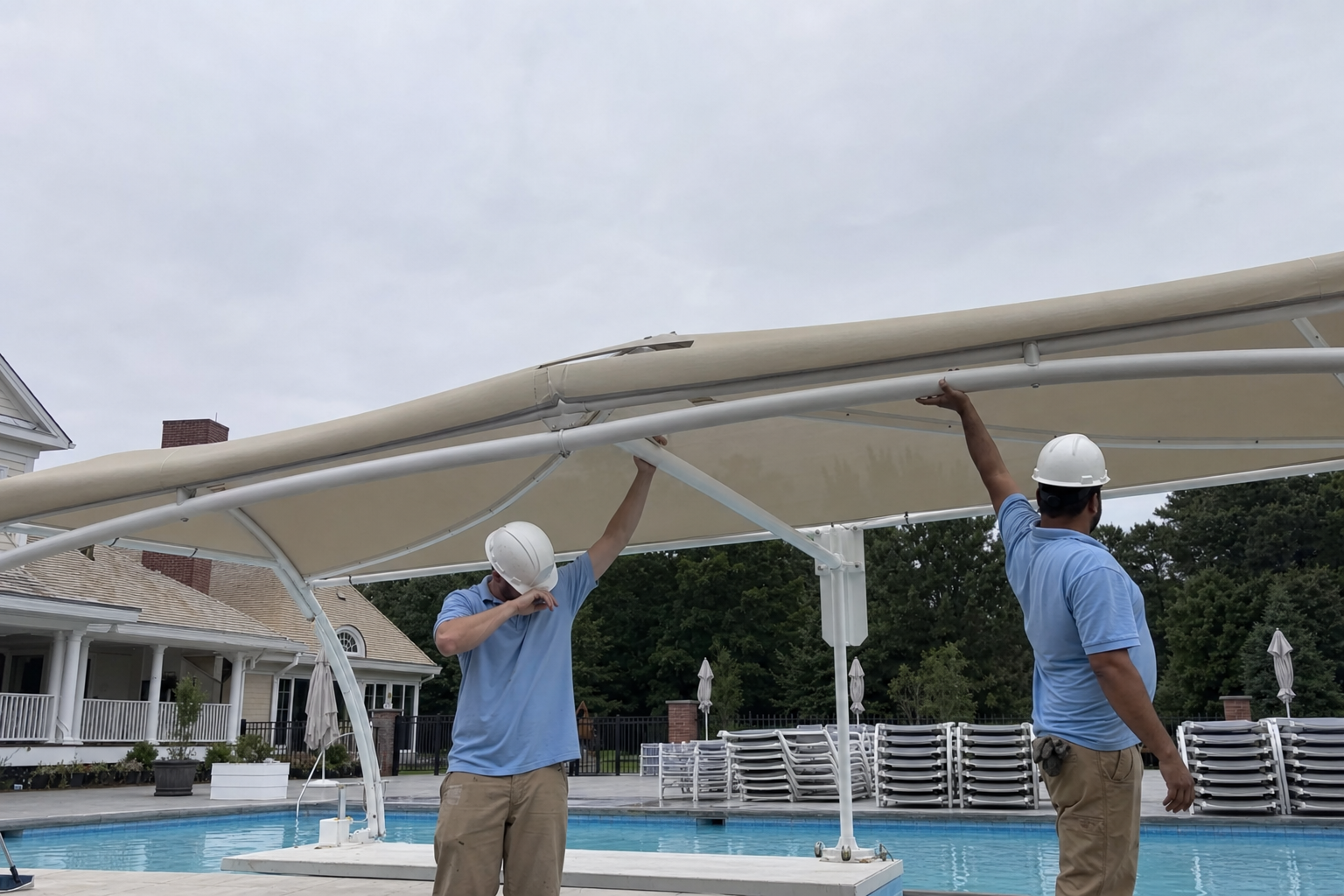 Commercial canvas shade canopy being installed over a swimming pool deck at a private club on Long Island, workers lifting frame members
