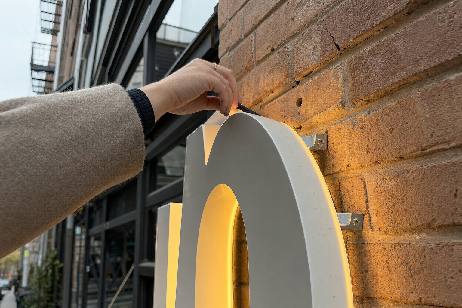 LED channel letters on a New York City commercial storefront facade, warm amber-white glow from individual letter returns