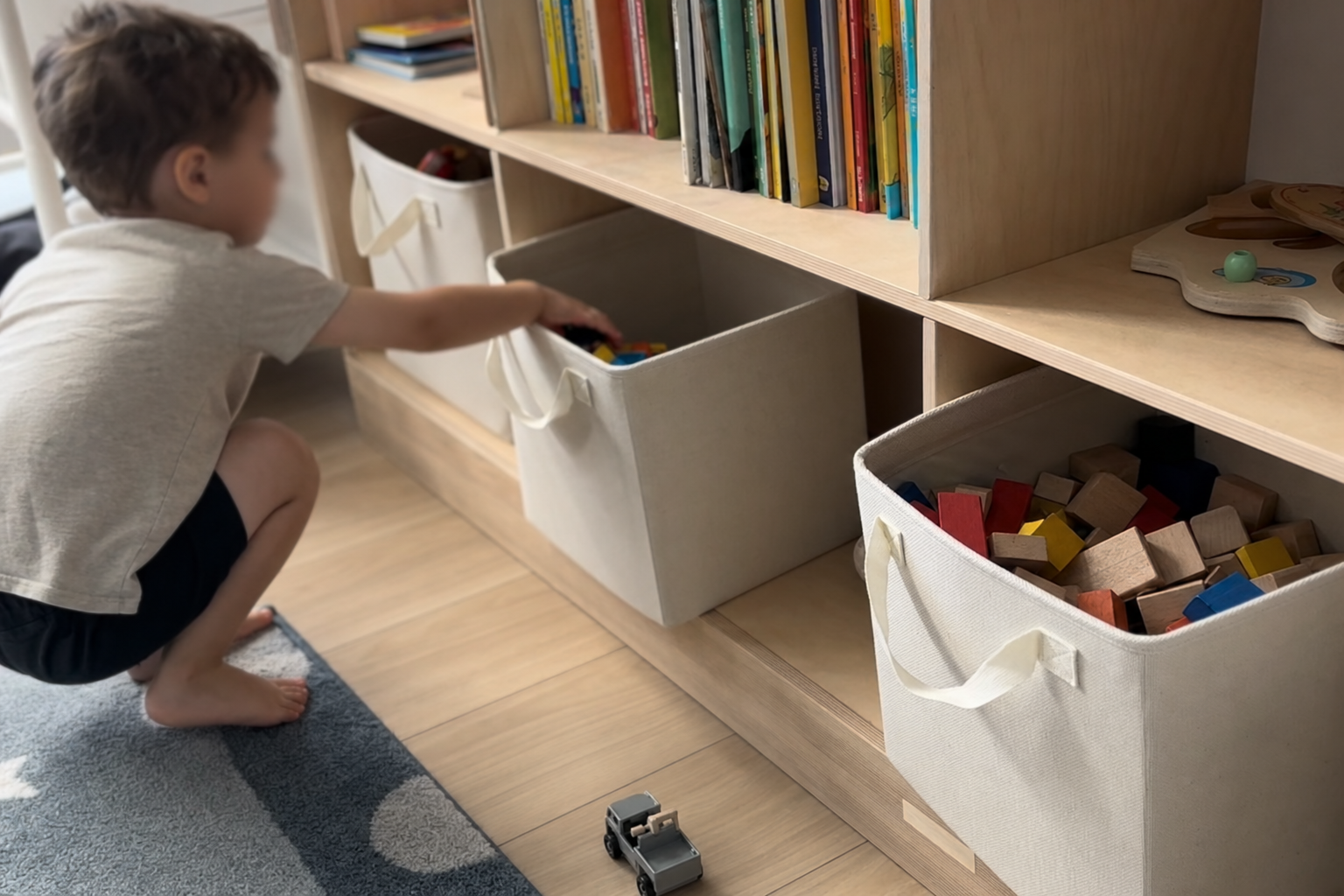 Organized kids room with low open shelves and labeled fabric bins that children can reach independently